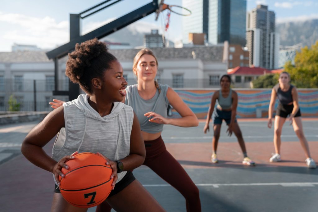 vrouw die een blessure heeft gehad heeft een basketbal in haar handen en speelt basketbal met andere vrouwen.